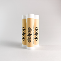 Three dollop lip balm tubes on a light gray background