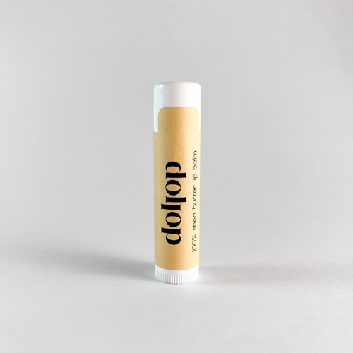 Lip balm with 'dollop' branding on a light gray background